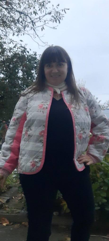 Steppjacke #118, Burdastyle 11/2025 ), genäht aus einem Steppstoff, weiß-grau gestreift mit Rosenmuster und rosa uni. Hier offen getragen mit einem weißen Sophie Scarf.